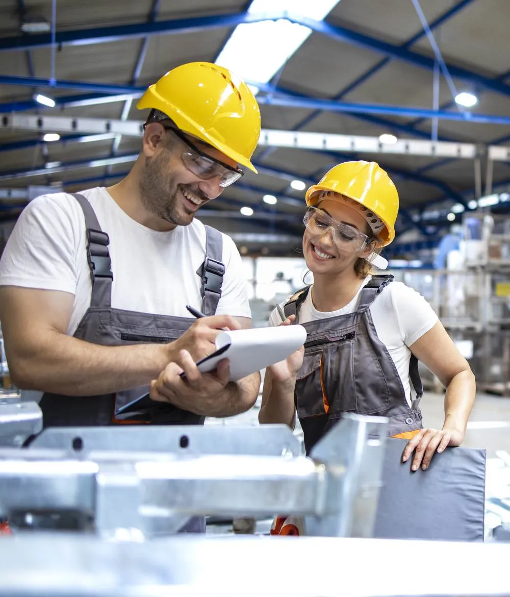 Zwei Mitarbeitende mit Helm bei der Qualitätskontrolle in einer Industriewerkstatt