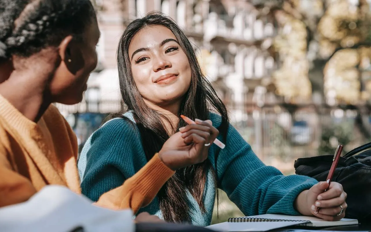 Two young people talking with their notebooks